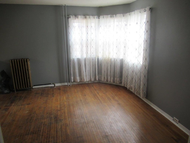 spare room featuring radiator and dark wood-type flooring