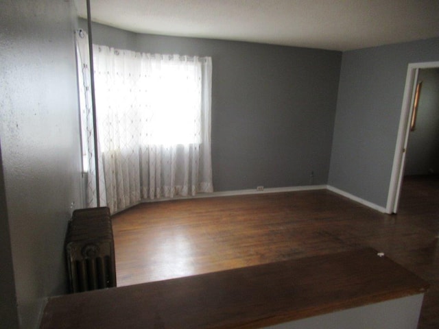 spare room with radiator heating unit and hardwood / wood-style floors