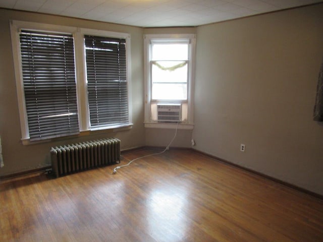 empty room featuring hardwood / wood-style flooring, cooling unit, and radiator