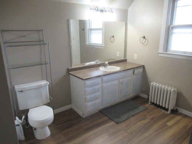 bathroom featuring vanity, toilet, radiator, and wood-type flooring