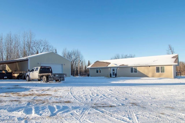 snow covered back of property featuring a garage and a carport