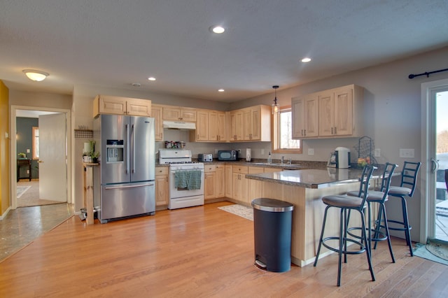 kitchen with hanging light fixtures, stainless steel refrigerator with ice dispenser, light hardwood / wood-style floors, kitchen peninsula, and white gas stove