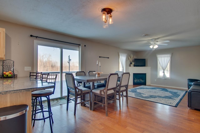 dining area with ceiling fan, a textured ceiling, and light wood-type flooring