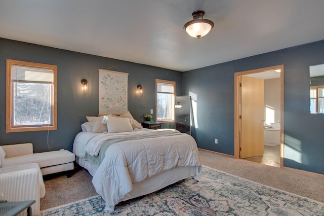 carpeted bedroom with ensuite bath and multiple windows