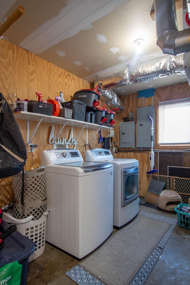 clothes washing area with wooden walls, electric panel, and independent washer and dryer