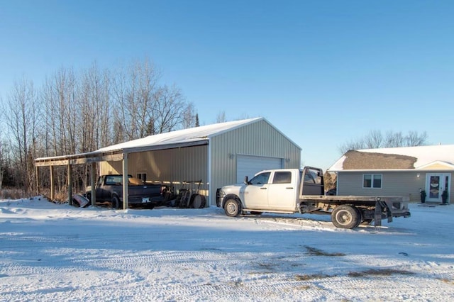 snow covered structure featuring a carport and a garage