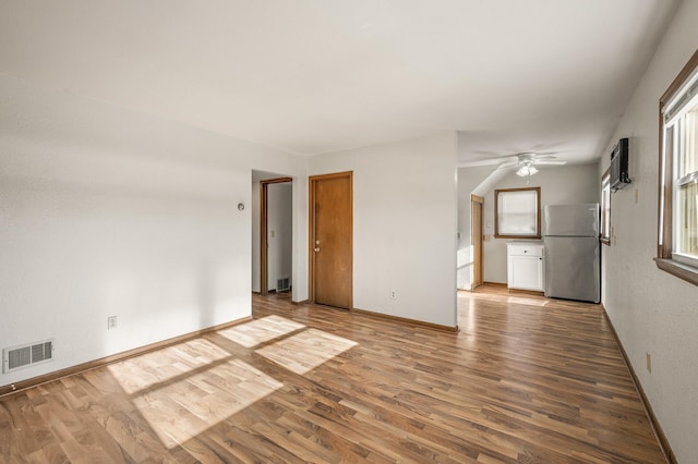 spare room with hardwood / wood-style floors, a wall unit AC, a healthy amount of sunlight, and ceiling fan