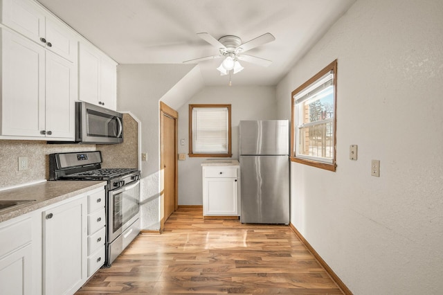 kitchen featuring white cabinetry, light hardwood / wood-style flooring, ceiling fan, stainless steel appliances, and backsplash