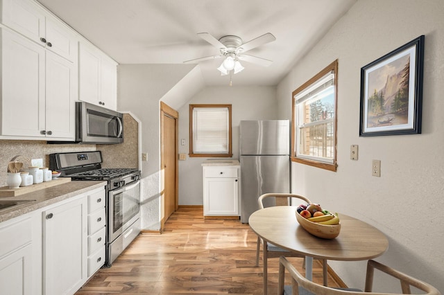 kitchen with ceiling fan, appliances with stainless steel finishes, white cabinetry, decorative backsplash, and light wood-type flooring