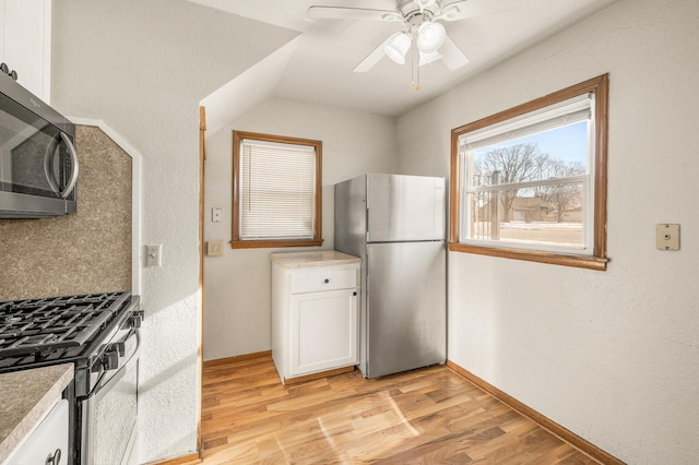 kitchen with ceiling fan, white cabinetry, backsplash, stainless steel appliances, and light wood-type flooring