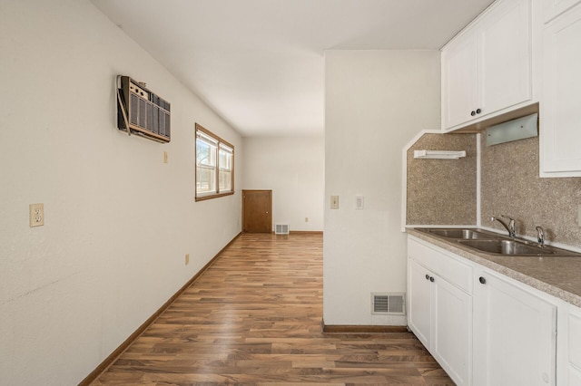 kitchen with white cabinetry, sink, backsplash, and a wall unit AC