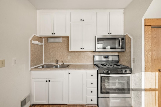 kitchen with white cabinetry, appliances with stainless steel finishes, sink, and backsplash