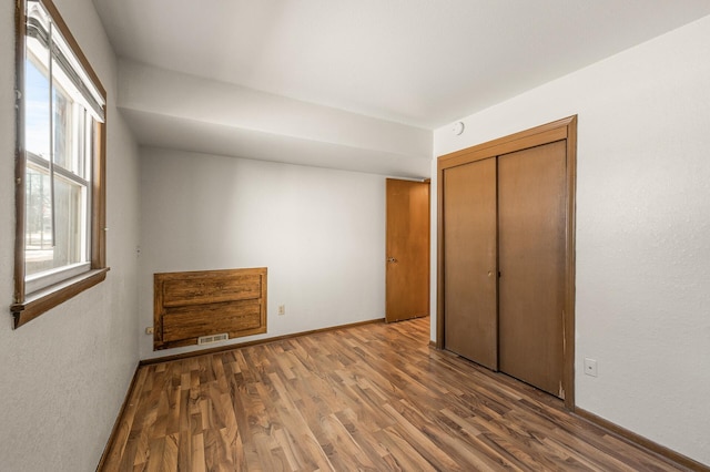 unfurnished bedroom with dark wood-type flooring, multiple windows, and a closet