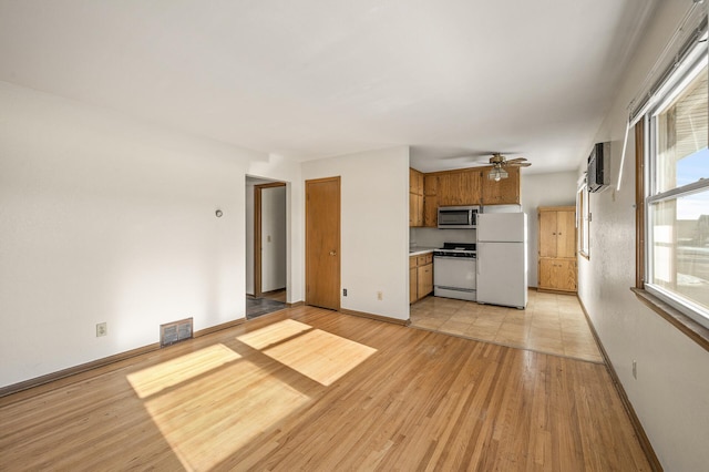 kitchen featuring ceiling fan, white appliances, light hardwood / wood-style flooring, and a wealth of natural light