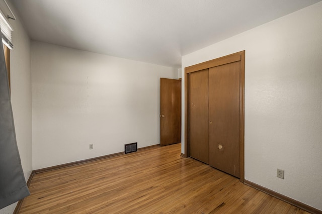 unfurnished bedroom with light wood-type flooring and a closet