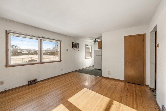 spare room with wood-type flooring, a wall unit AC, and ceiling fan