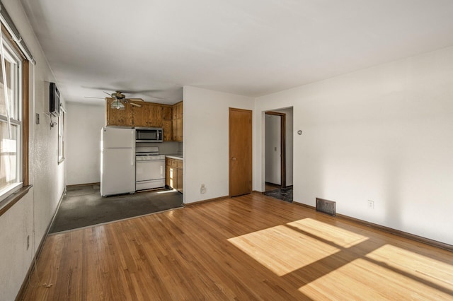 kitchen with dark hardwood / wood-style flooring, a wall mounted air conditioner, ceiling fan, and white appliances