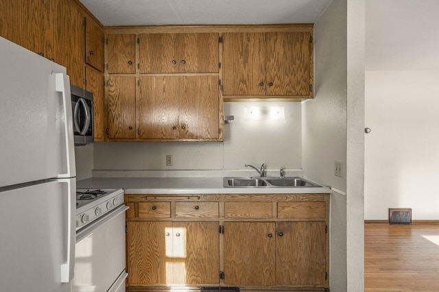 kitchen featuring sink, white appliances, and light hardwood / wood-style flooring