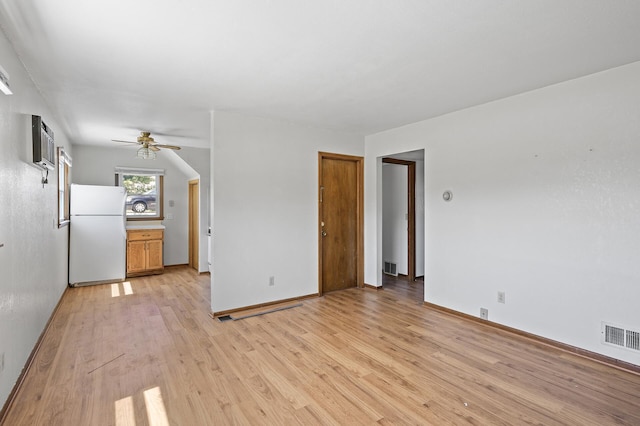 unfurnished living room featuring an AC wall unit, light wood-style floors, a ceiling fan, and baseboards