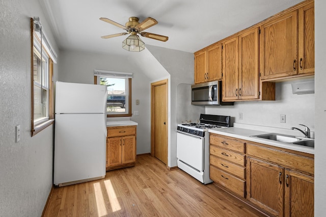 kitchen featuring white appliances, a sink, brown cabinets, and light wood-style floors