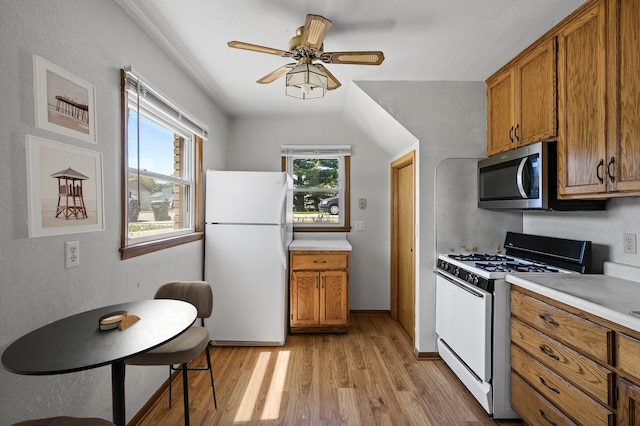 kitchen with freestanding refrigerator, range with gas stovetop, stainless steel microwave, and brown cabinets
