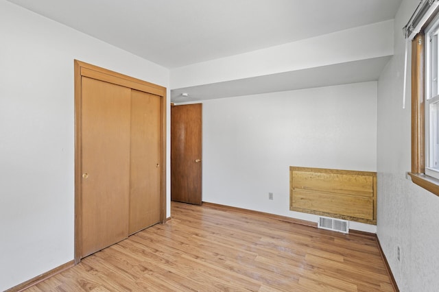 unfurnished bedroom featuring light wood finished floors, a closet, and baseboards