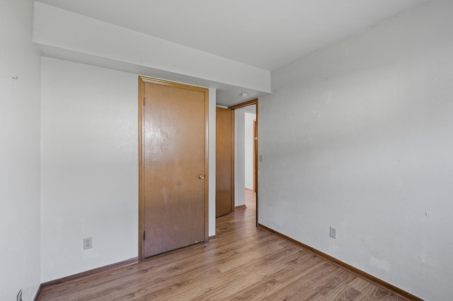 unfurnished bedroom with light wood-style flooring, a closet, and baseboards
