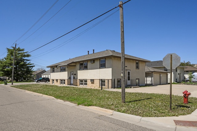 view of front of home featuring stucco siding, driveway, a front yard, an attached garage, and brick siding