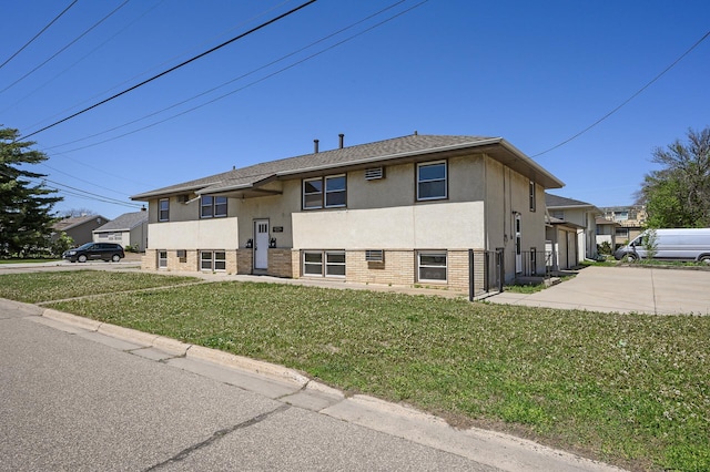 split foyer home featuring stucco siding, brick siding, and driveway