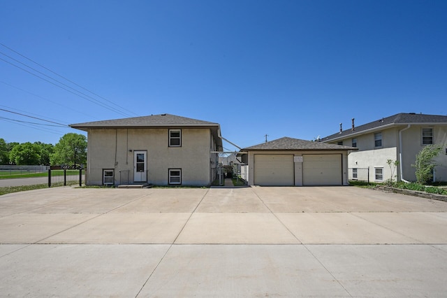 back of property featuring stucco siding, fence, and a detached garage