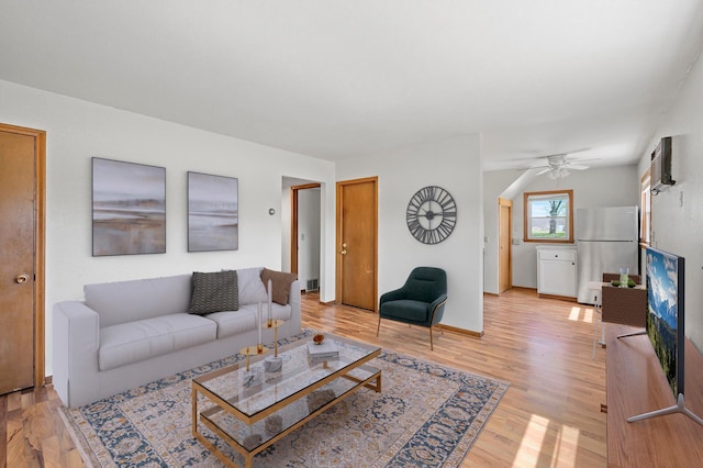 living room featuring light wood finished floors, a ceiling fan, and baseboards
