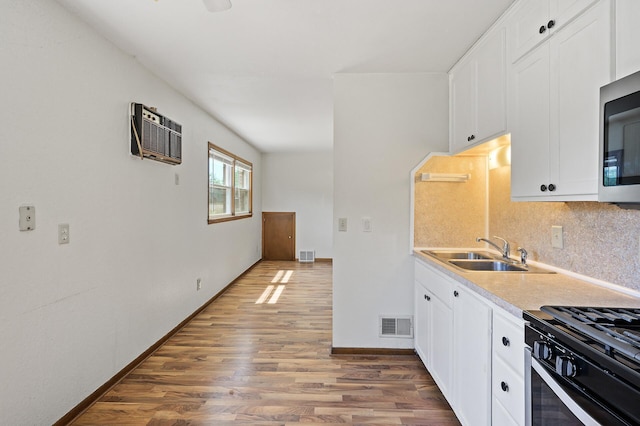 kitchen featuring a sink, wood finished floors, backsplash, and white cabinets