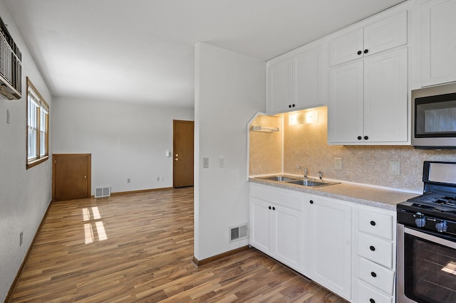kitchen featuring appliances with stainless steel finishes, wood finished floors, decorative backsplash, and a sink