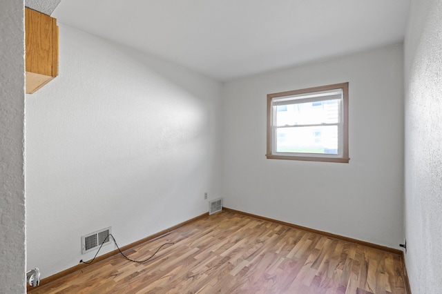 spare room featuring light wood-type flooring and baseboards