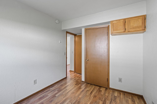 unfurnished bedroom with light wood finished floors, a closet, and baseboards