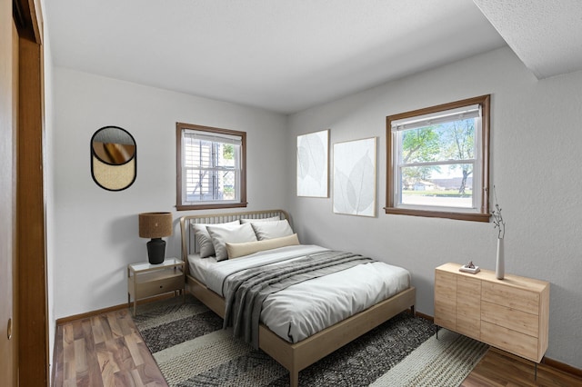 bedroom featuring multiple windows, wood finished floors, and baseboards