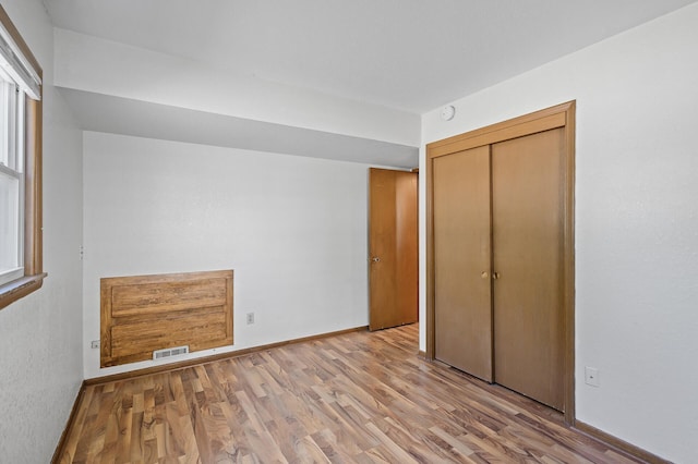 unfurnished bedroom featuring wood finished floors, a closet, and baseboards