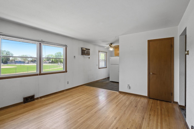 unfurnished room with wood finished floors, a ceiling fan, a wall mounted air conditioner, and baseboards
