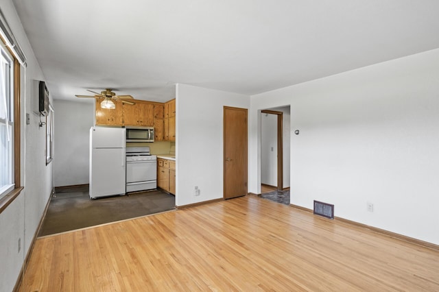 kitchen with white appliances, a ceiling fan, light countertops, wood finished floors, and baseboards