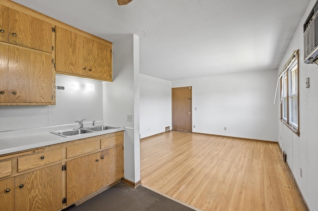 kitchen featuring a sink, light countertops, light wood-style floors, and baseboards