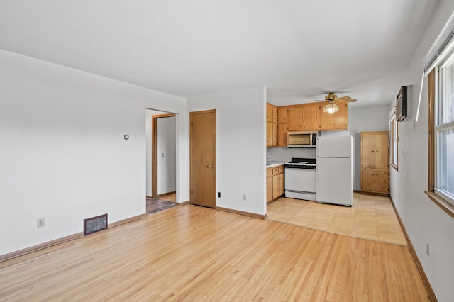 kitchen featuring white appliances, a ceiling fan, light wood-style flooring, light countertops, and baseboards