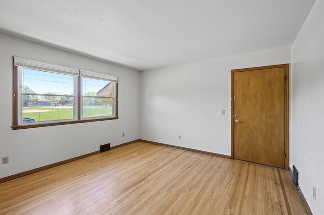 spare room featuring light wood-type flooring and baseboards