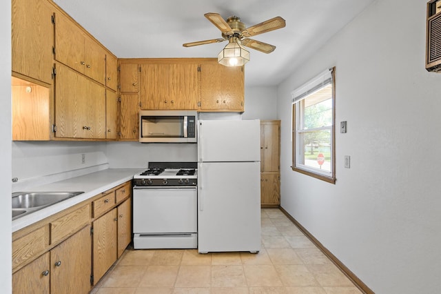 kitchen with white appliances, a ceiling fan, baseboards, light countertops, and a sink