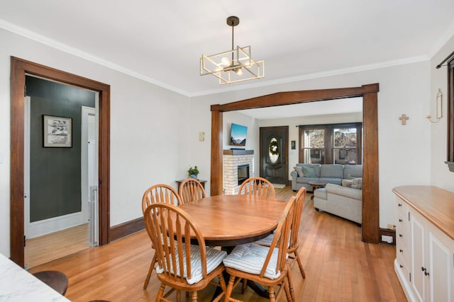 dining room with crown molding, a fireplace, and light wood-type flooring