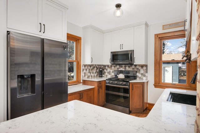 kitchen with tasteful backsplash, white cabinetry, sink, light stone counters, and stainless steel appliances