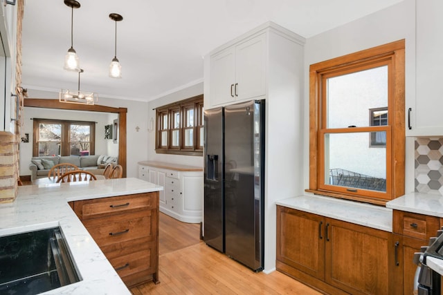 kitchen featuring pendant lighting, stainless steel fridge, light stone countertops, and white cabinets