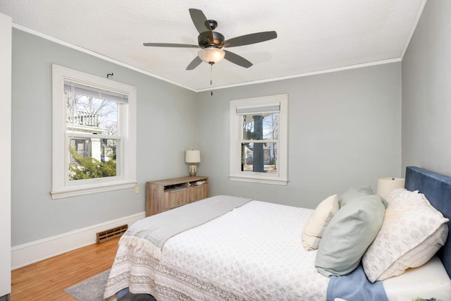 bedroom featuring wood-type flooring, ornamental molding, ceiling fan, and a textured ceiling