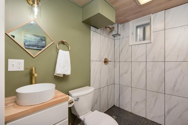 bathroom with tiled shower, vanity, and toilet