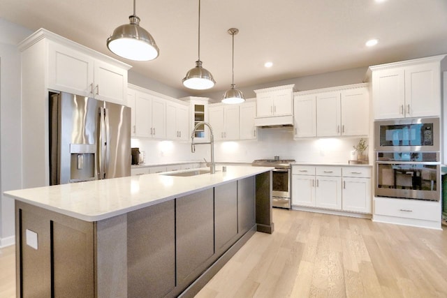 kitchen featuring sink, decorative light fixtures, light wood-type flooring, appliances with stainless steel finishes, and white cabinets