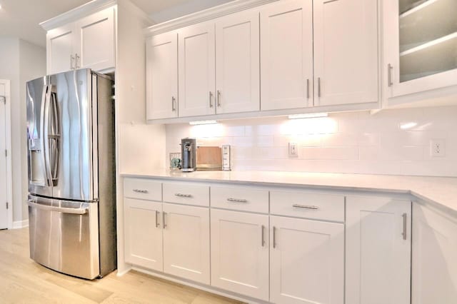 kitchen with backsplash, stainless steel fridge with ice dispenser, light hardwood / wood-style flooring, and white cabinets